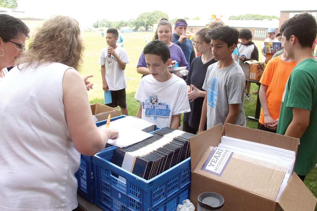FILLING ORDERS: Michelle Curran, who advised the school’s yearbook club, hands out copies. The books that had to be pre-ordered cost $36 for a hardcover copy and $30 for a soft copy. For the first time, Curran provided at no charge memento autograph books to the students.